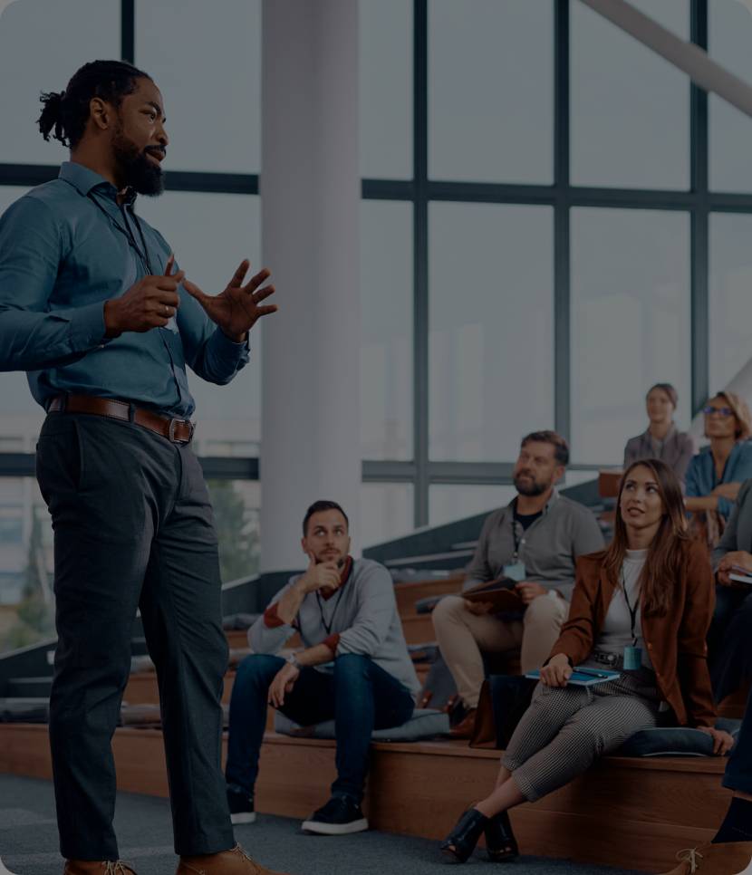 Man presenting to an engaged group in a modern, casual setting.