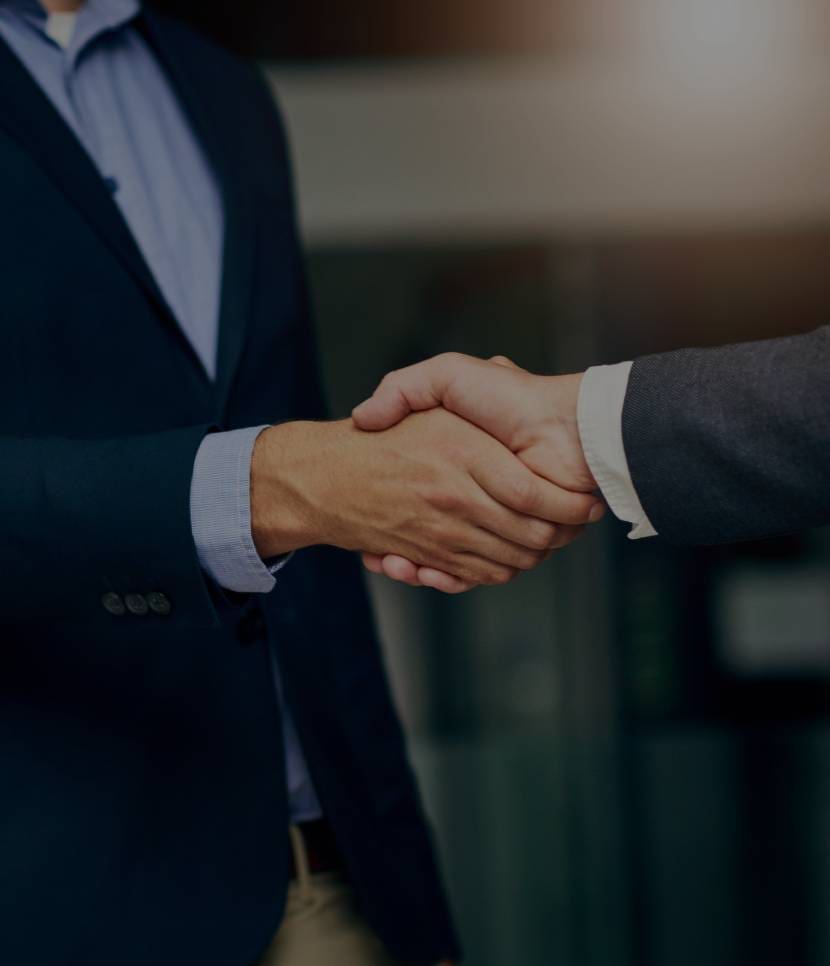 Two professionals shaking hands in a formal setting.